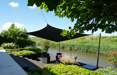 Foto: Nesling schaduwdoek boven terras aan water in grijs