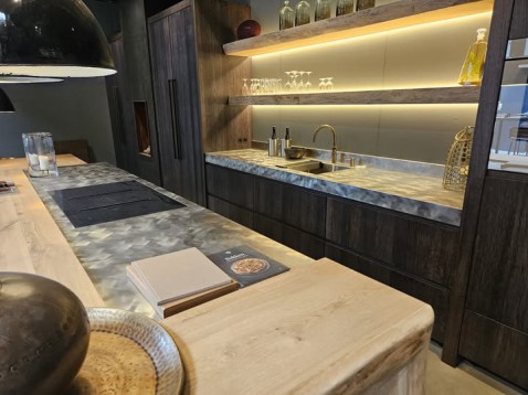 Foto : Karaktervolle showroomkeuken met wild geborsteld RVS en warme houttinten