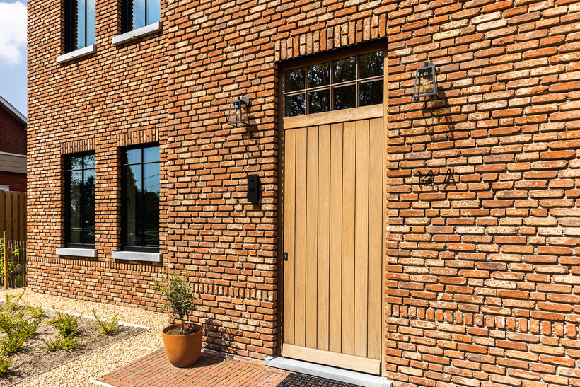 Landelijke houten voordeur met groeven en bovenlicht met verdelingen.