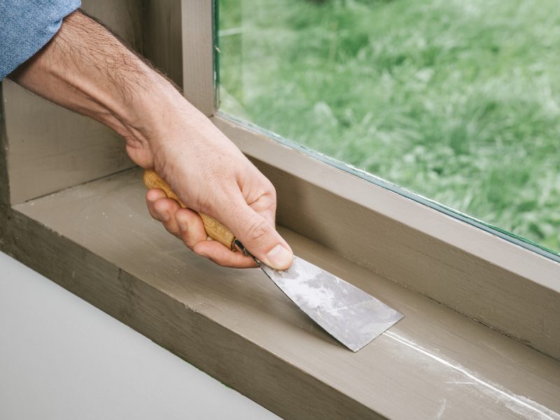 Foto: houtvuller uitsmeren met plamuurmes op houten kozijn 1 e1762267759326