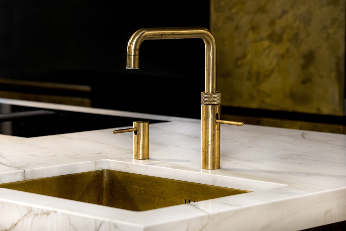 Foto: Messing Quooker en messing spoelbak in Marmer werkblad